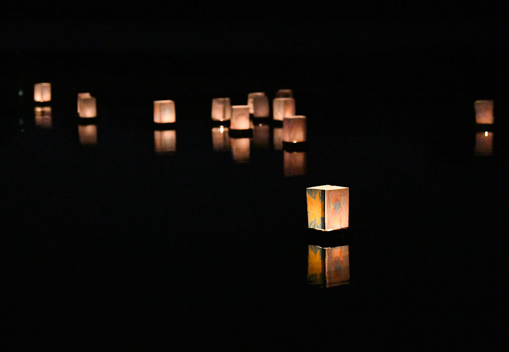 Floating lanterns drift away from the shore